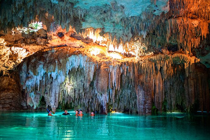 Daylight falling through a collapsed cenote roof onto clear green water inland from Playa del Carmen